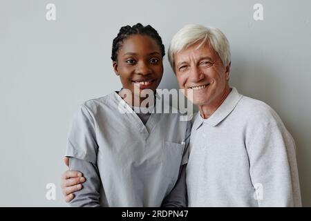 Rivedi il ritratto di una giovane donna nera come infermiera e un uomo anziano che sorridono insieme alla macchina fotografica Foto Stock