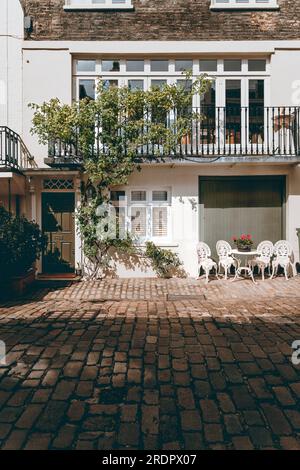 Posti a sedere all'aperto di fronte a una graziosa casa Foto Stock