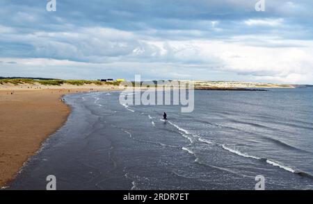 Sandy Bay e la marea arrivano a Porthcawl in una soleggiata serata di luglio con la maggior parte del cielo grigio e nuvoloso con molta gente sulla spiaggia Foto Stock