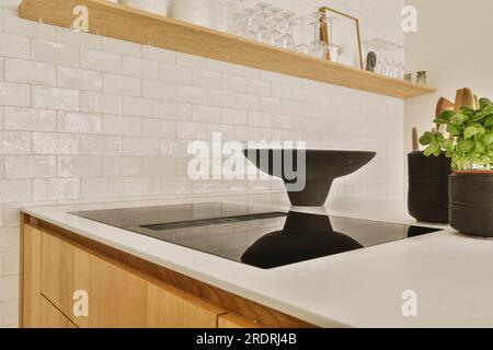 una cucina con piastrelle bianche sulla parete e armadi in legno nei ripiani sono realizzati in granito nero Foto Stock