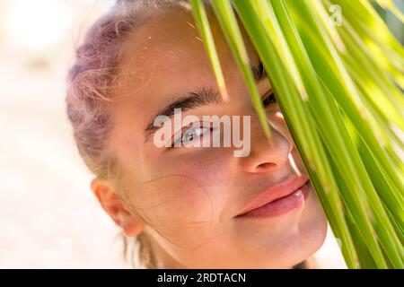 Ritratto di una giovane donna sorridente con foglie di palma Foto Stock