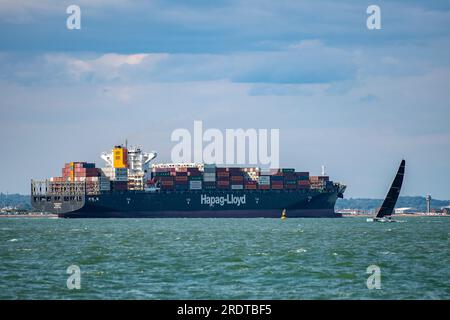 grande nave container che passa per uno yacht da corsa a solent, al largo dell'isola di cowes di wight. Foto Stock