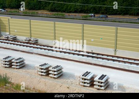 Posa di nuovi binari ferroviari. Materiali da costruzione in acciaio e traverse. Linea ferroviaria ad alta velocità ICE. Auto sull'autostrada. Wendlingen, Ulm, A8. Foto Stock