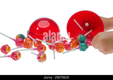Vista ravvicinata delle mani dell'uomo che reggono un grande pacchetto chupa chups in plastica per diversi caramelli. Foto Stock