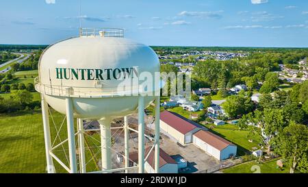 Primo piano della torre dell'acqua di Huntertown con edifici e alberi distanti Foto Stock