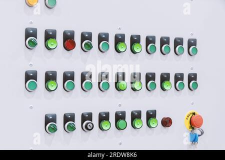 Pulsanti rotondi del pannello di controllo industriale sulla schermatura in verde e rosso Foto Stock