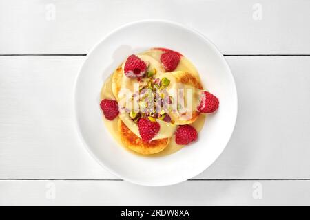 Frittelle dolci al formaggio con crema pasticcera, lamponi e pistacchi Foto Stock