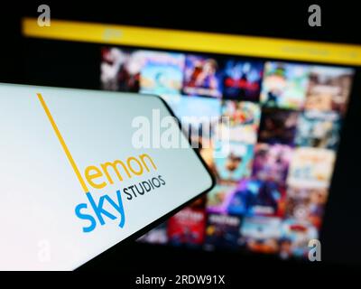 Smartphone con logo della società malese di videogiochi Lemon Sky Studios sullo schermo di fronte al sito Web. Mettere a fuoco il display centrale sinistro del telefono. Foto Stock