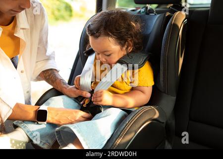 Mamma asiatica seduta Giù bambino in seggiolino auto bambino dentro Foto Stock