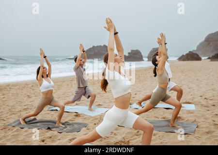 Stile di vita sano e equilibrato. Lezione di yoga sulla spiaggia oceanica al mattino con pose da guerriero con tranquille emozioni rilassanti Foto Stock