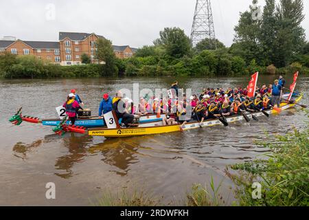 23 luglio 2023 - River Mersey, Warrington, Cheshire, Inghilterra - un Dragon Boat Festival organizzato lungo il fiume Mersey a Warrington. Tenuto al Rowing Club e nonostante la continua pioggia durante la giornata, un certo numero di Dragon Boats gareggiarono per trovare un eventuale vincitore. Le barche pagaiano all'indietro per arrivare al centro del fiume. L'evento è stato quello di raccogliere fondi per il St Rocco's Hospice, che ha lo scopo di fornire assistenza e supporto di qualità a quelle persone e ai loro cari con malattie limitanti la vita che vivono nell'area di Warrington, per consentire a ogni persona di trovare conforto, speranza, forza e pace. Foto Stock