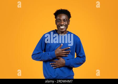 Un ragazzo africano Millennial riconoscente che tiene le mani sul petto Foto Stock