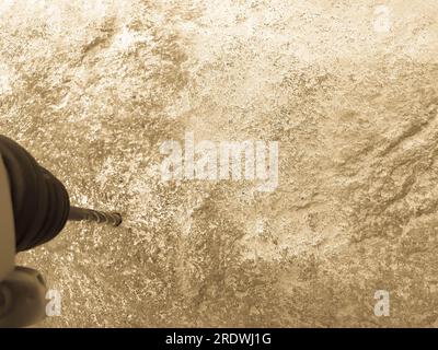 Una robusta punta in ferro duro perfora un foro in una grande pietra grigia. Vista ravvicinata. Lo sfondo. Foto Stock