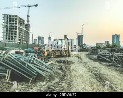 cantiere di un nuovo distretto. attrezzature e materiali da costruzione gialli in loco. sullo sfondo di case alte. costruzione Foto Stock