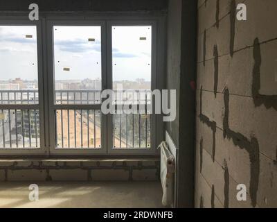 Una grande finestra panoramica in vetro francese con un profilo in plastica in un nuovo edificio con disposizione libera, in un appartamento senza riparazione di edifici. Foto Stock
