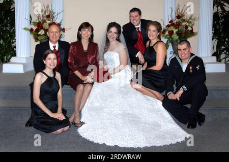 Sposa e famiglia siedono sui gradini della chiesa prima del matrimonio. Tutti sorridono e sono felici. Ci sono madre e padre, e due sorelle e un fratello. Foto Stock