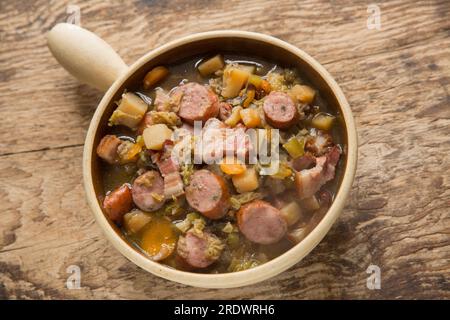 Un eintopf fatto in casa in una pentola a cottura lenta con verdure in gran parte radicali e cavolo con salsiccia di maiale polacca alle erbe e pancetta affumicata. Inghilterra U Foto Stock