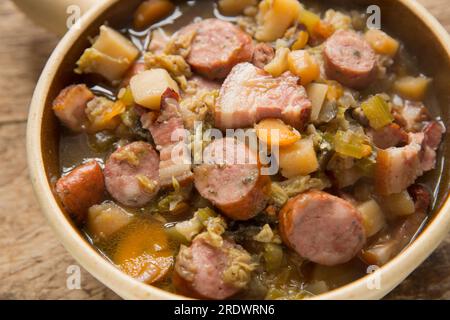 Un eintopf fatto in casa in una pentola a cottura lenta con verdure in gran parte radicali e cavolo con salsiccia di maiale polacca alle erbe e pancetta affumicata. Inghilterra U Foto Stock