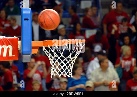 La pallacanestro rotante utilizza il tabellone per rimbalzare verso la porta. La palestra affollata assiste a una partita di basket delle scuole superiori. Foto Stock