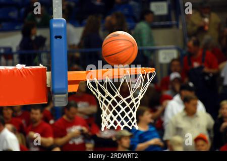L'affollata palestra guarda un pallacanestro che gira nel mirino in metallo arancione e nella rete bianca. Foto Stock