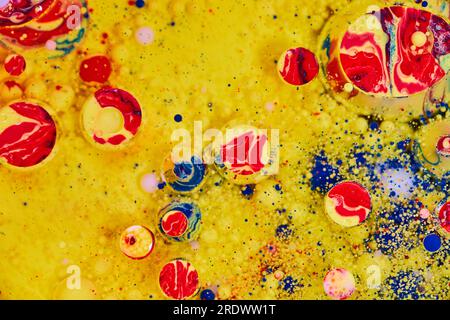 Pittura acrilica gialla con olio bollente di rosso e blu come elemento di sfondo Foto Stock