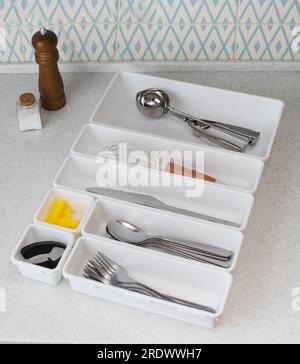 Vassoi organiser in plastica con un set di posate sul tavolo della cucina. Sistema di archiviazione. Foto Stock