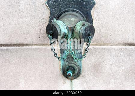 City shutoff valve is capped and eroding on city street.  Green copper erosion covers chain and caps. Stock Photo