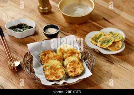 Jeon Hobak o zucchine fritte in padella, tradizionale pancake di verdure coreana servita con salsa di soia, semi di sesamo e Makgeolli Foto Stock