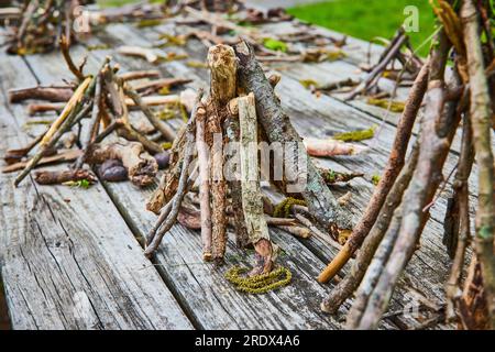 Tavolo da picnic in legno ricoperto da piccoli pali di teepee a bastone Foto Stock
