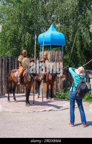 Kazakistan, Huns Ethno Village. Turista che fotografa il cavaliere in costume nomade all'ingresso dell'Ethno-Village. Foto Stock