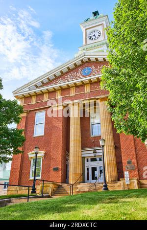 Tribunale verticale in mattoni rossi con torre dell'orologio con cielo blu e albero verde Foto Stock
