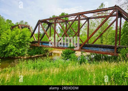 Foto estiva del fiume Kokosing con ponte ferroviario ed erba Foto Stock