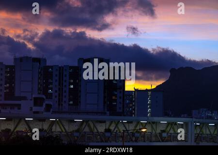 Il famoso punto di riferimento di Kowloon, la montagna Lion Rock, si trova sul lato destro e gli alloggi pubblici sul lato sinistro, con lo sfondo del tramonto. Foto Stock