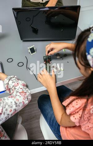 Studentessa che avvita i circuiti elettrici della macchina in classe di robotica Foto Stock