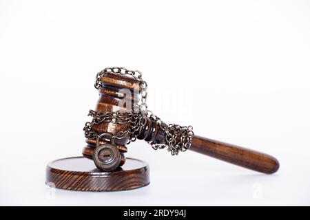 Il martelletto del giudice è legato con una catena al lucchetto su sfondo bianco, non alla legalità della sentenza e all'arresto del giudice Foto Stock