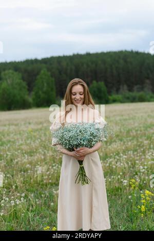 Giovane donna sorridente con bouquet di fiori sul campo Foto Stock