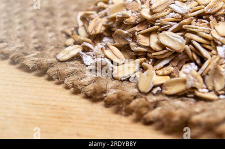 Fiocchi d'avena sopra un tessuto di iuta su una superficie di legno Foto Stock