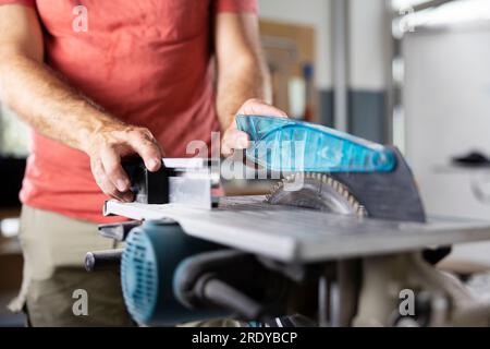 Mani di falegname che lavorano su sega circolare in officina Foto Stock