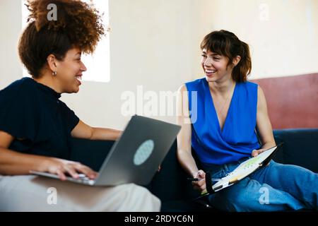 Felici donne d'affari sedute sul divano e che discutono insieme Foto Stock