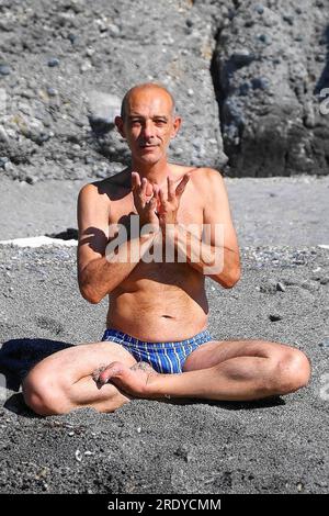 L'uomo di mezza età pratica yoga in spiaggia Foto Stock