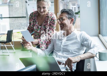 Donna d'affari sorridente e uomo d'affari che guarda la fotografia in ufficio Foto Stock