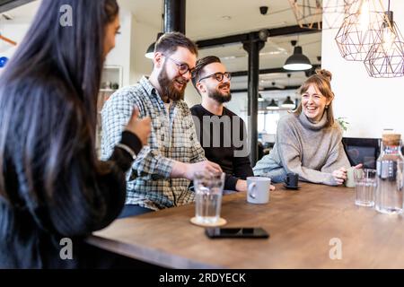 Uomini d'affari felici e donne d'affari che si prendono una pausa e parlano tra loro in ufficio Foto Stock