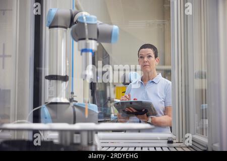 Ingegnere concentrato che esamina le macchine robotiche nel settore industriale Foto Stock