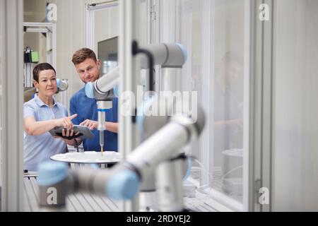 Il tecnico spiega la macchina robotica al collega in fabbrica Foto Stock