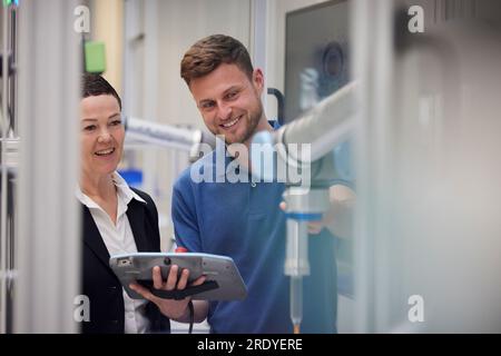 Collega sorridente che spiega la macchina al responsabile del settore Foto Stock