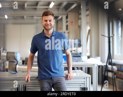 Tecnico sorridente che si appoggia al tavolo nell'industria Foto Stock