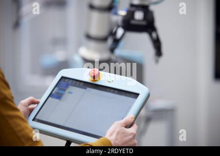 Mani di un ingegnere che tiene il controller del robot nel settore industriale Foto Stock