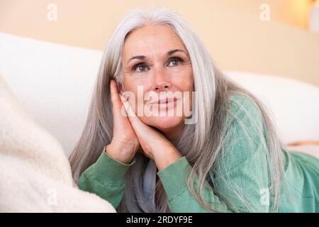 Donna matura premurosa con i capelli grigi a casa Foto Stock