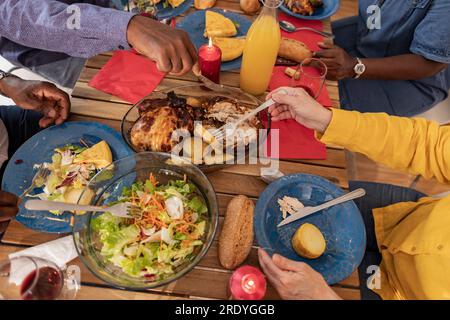 Amici anziani multiculturali che si godono cibo e bevande a tavola a casa Foto Stock
