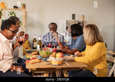 Felici amici multiculturali anziani che mangiano a cena Foto Stock